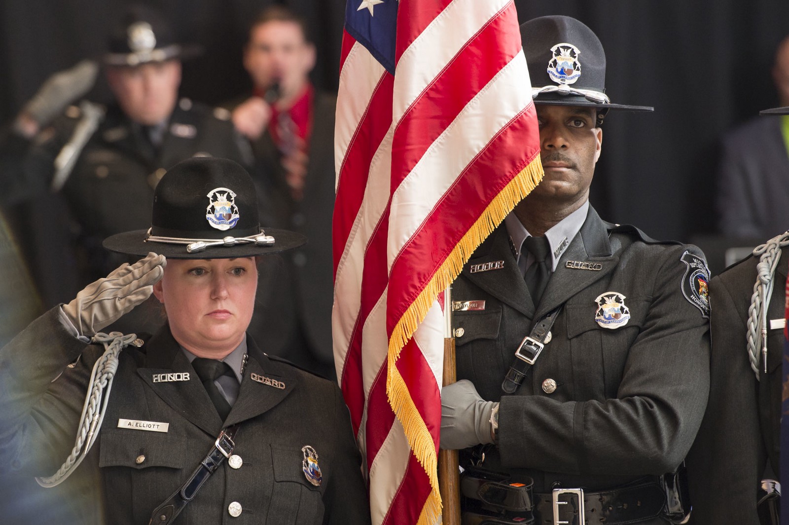 MDOC Honor Guard. A man is holding the American flag and a woman is saluting.